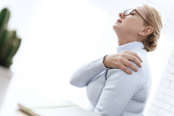 una mujer aferrándose a su hombro que duele. - sport massaging accident adult fotografías e imágenes de stock