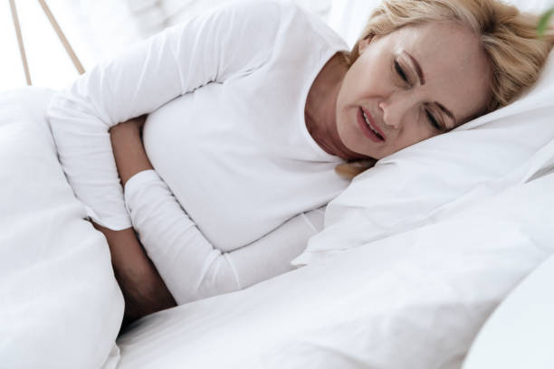 istock A white woman has a stomach ache lying in bed. 1289372109