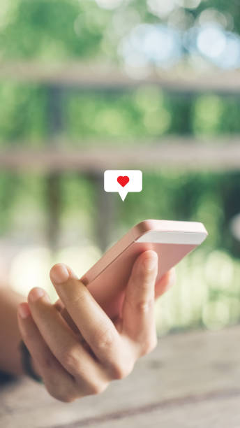 istock Man hand using smartphone with heart icon at coffee shop background. Technology business and social lifestyle concept. 1289372964