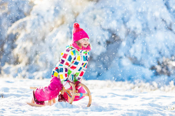 istock Girl on sleigh ride. Child sledding. Kid with sledge 1289374403