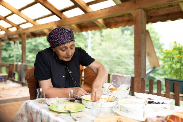 Senior woman having breakfast and drinking tea in a traditional glass a sofa