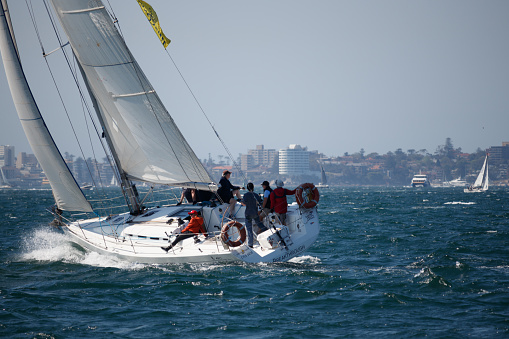 Sydney, NSW, Australia. October 3, 2020: Breakthrough, a 40 foot sailboat during a windy spot in Sydney Harbor. Choppy water. Manly in the distance. Selective focus