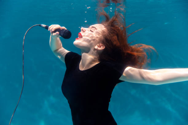 cantante con micrófono bajo el agua. copiar espacio. arte - blowing hair audio fotografías e imágenes de stock