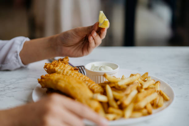 istock Young asian woman ready to squeeze a lemon slice over fish and chips 1289381183