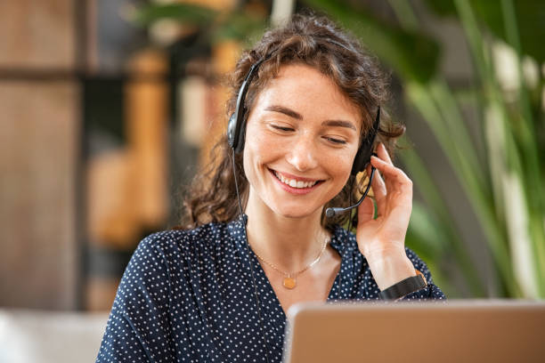 smiling woman talking to customer on headphones - call center imagens e fotografias de stock