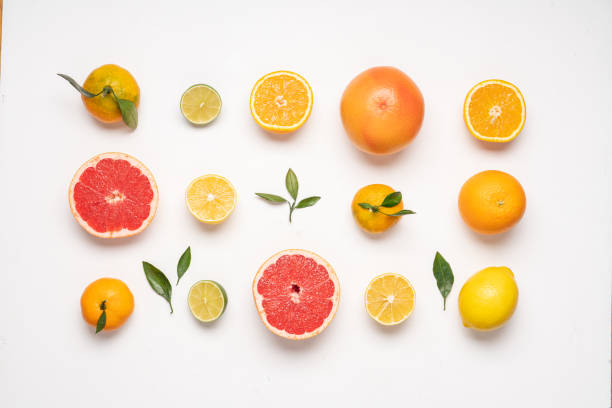 diseño creativo de alimentos cuidadosamente dispuestos de cítricos y hojas sobre fondo blanco - fruta cítrica fotografías e imágenes de stock