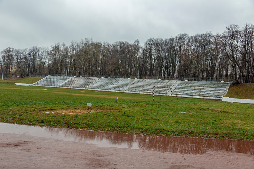 Part of the destroyed city stadium with soccer field on a cloudy day