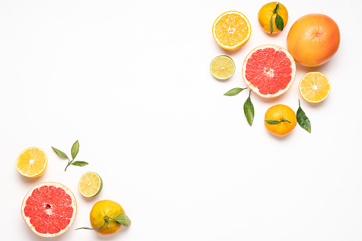 Grapefruit in a metal plate. Slices and whole fruits of juicy fresh grapefruit on a light background