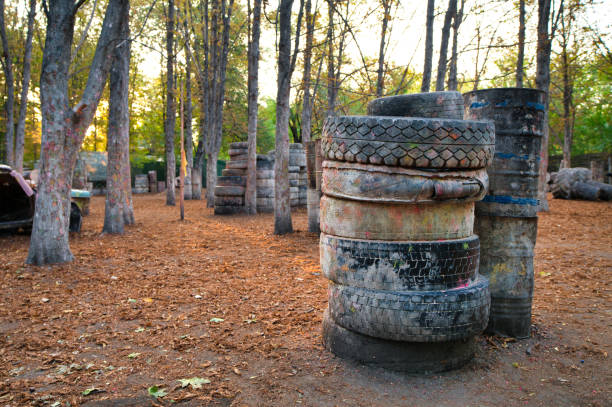 istock Old rusty barrels and damaged tires on a paintball base 1289384928