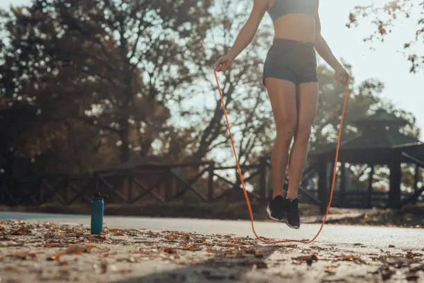 Athlete woman exercising with skipping ropes outdoors.