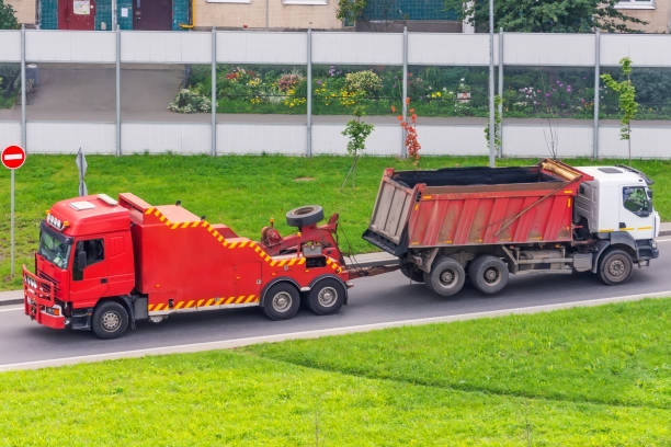Low tow truck trailer with car in road. Auto vehicle with Carrier transporter hauler on driveway. European transport logistics at haulage work transportation. Haul on highway.