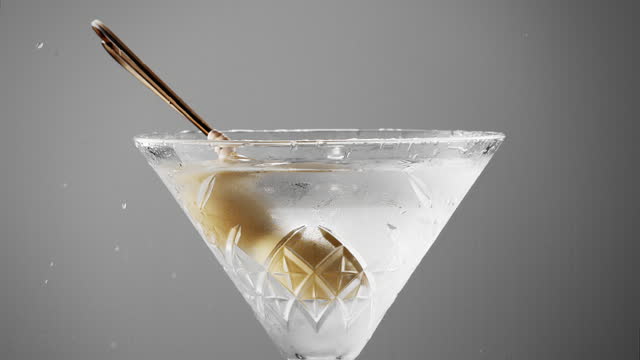 olives garnish splashing into martini close up