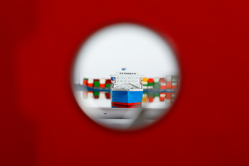 Container ship model on a digital tablet. View through the hole of a red ring binder