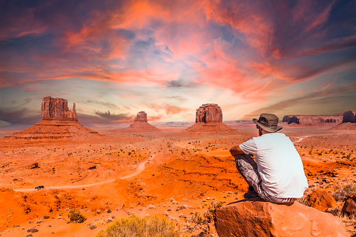 A young man in a white t-shirt in Monument Valley National Park at the visitor center at sunset, Utah. United States