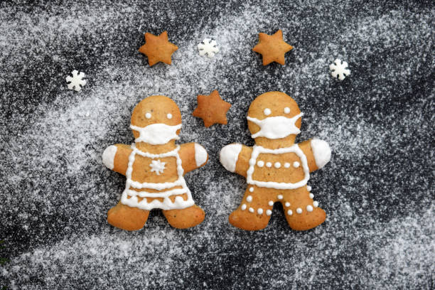istock Cute gingerbread couple with protective face masks on black sugared background with stars and small sugar snowflakes 1289397026