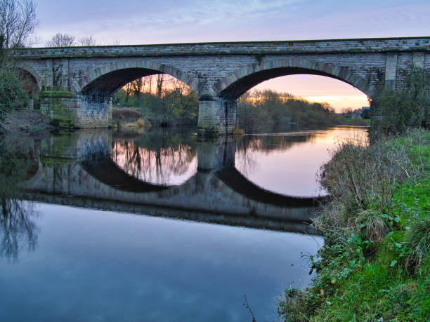 Disused Victorian railway viaduct crossing River Wharfe, Tadcaster, North Yorkshire, England, Britain Arched Victorian viaduct with reflections in river river wharfe stock pictures, royalty-free photos & images