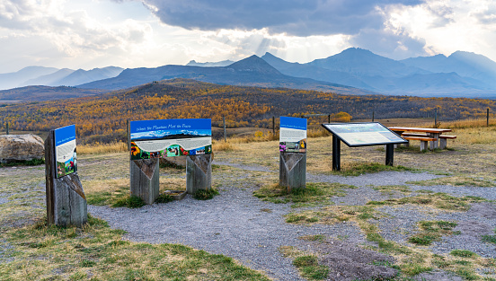 Waterton Scenic Spot, Waterton Lakes National Park. Vast prairie and forest in beautiful autumn foliage season. Sunlight passing blue sky and clouds on mountains. Alberta, Canada.