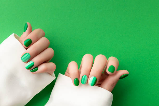 istock Beautiful groomed woman's hands with spring summer nail design on green background. 1289402998