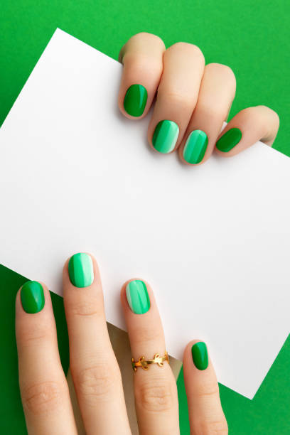 istock Womans hands with trendy green manicure holding postcard 1289403065