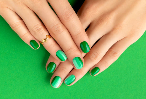 Beautiful groomed woman's hands with spring summer nail design on green background