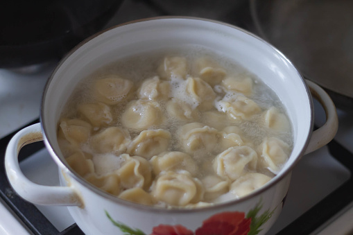 Dumplings are cooked in a pot on the stove in the kitchen.