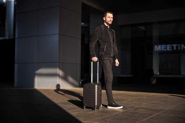 istock Confident traveler walking with his suitcase alone 1289408025