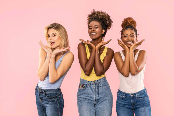 Three beautiful multiethnic women smiling and having fun together. Funny photo of three multiracial women posing on pink studio background, smiling and having fun together. Happy lifestyle concept. girl band stock pictures, royalty-free photos & images