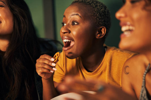 Nothing gets us going like a good horror Shot of three friends eating snacks while watching something together binge-watching stock pictures, royalty-free photos & images