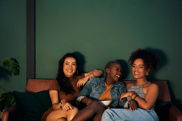 Enjoying a night in with the squad Shot of three friends eating snacks while watching something together ladies night stock pictures, royalty-free photos & images