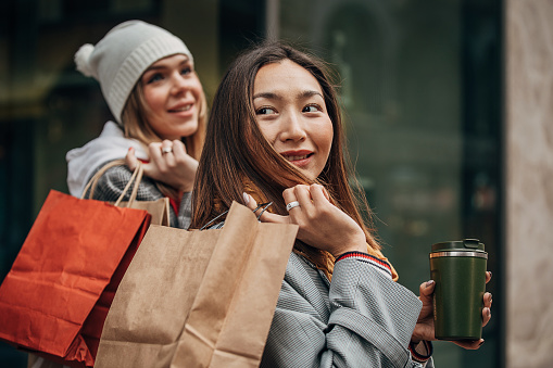 Two women, female friends on the street in city, they went shopping together.