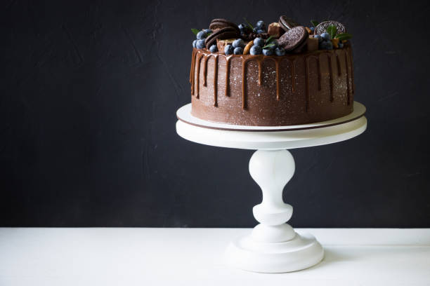 istock Chocolate cake with blueberries on a stand, black background 1289415420
