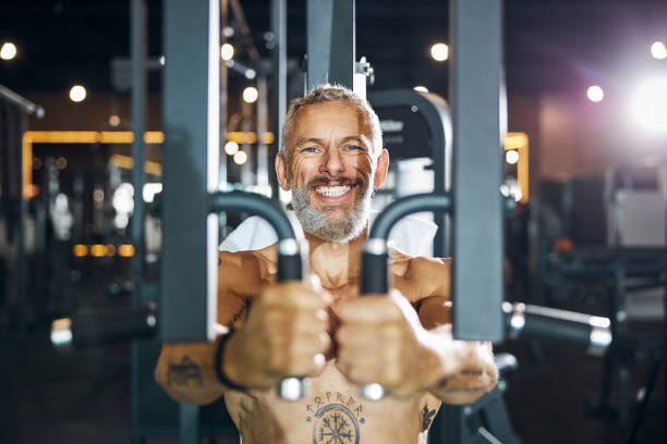 fröhlicher bodybuilder genießt sein krafttraining - chest fly stock-fotos und bilder