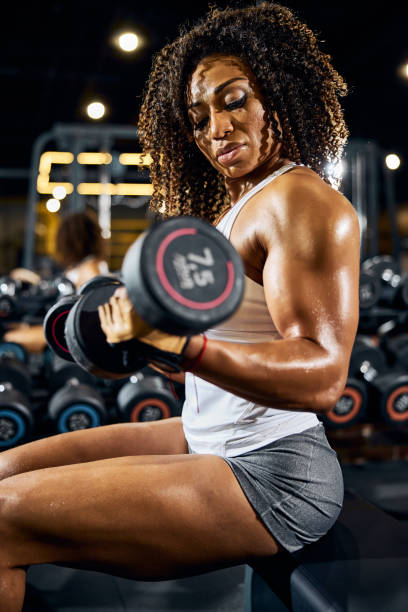 istock Female bodybuilder doing the seated dumbbell bicep curl 1289416109