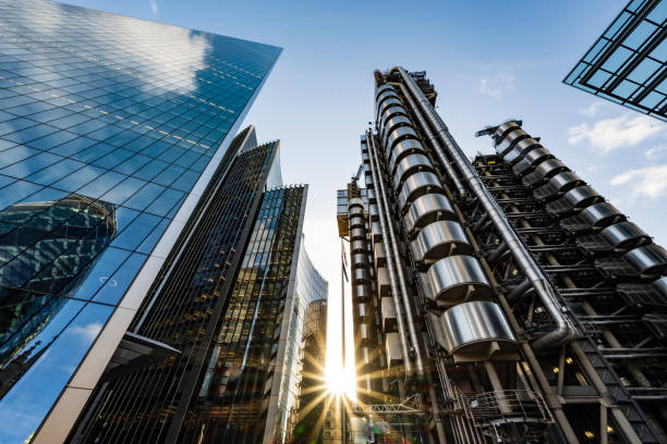 Steel and glass facades of landmark London architecture Low angle view with lens flare of modern office buildings in financial district reflecting one another in late afternoon under blue sky. inner london stock pictures, royalty-free photos & images