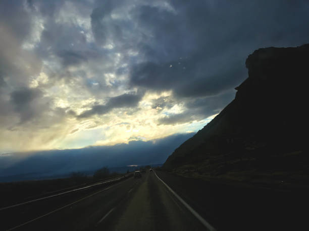 istock Driving on Interstate 70 at Sunset with Automobiles in Background and Prominent Mountain Silhouettes and Extreme Skies 1289418708