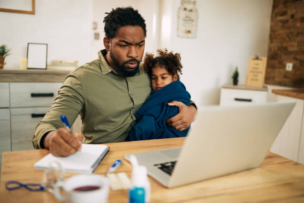 istock African American father working at home while holding his small daughter is feeling ill. 1289419199