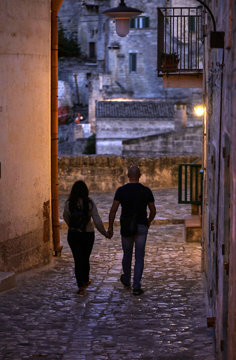 Matera, Italy - September 14, 2019: Couple during a walk on Cobblestone street in the Sassi di Matera a historic district in the city of Matera. Basilicata. Italy