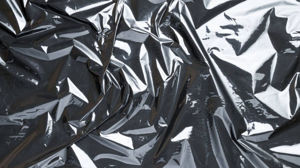 istock Smooth texture. Black shiny film bag pattern. Wrap transparent dark cellophane background. Real texture of polyethylene foil. 1289420611