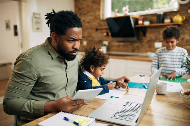 istock Black father using touchpad and working on laptop while being with his kids at home. 1289420851