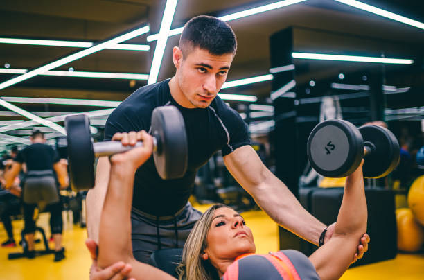 istock Personal trainer helping woman at gym 1289421340