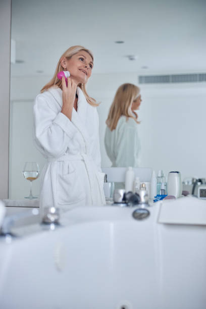 bonita rubia dama caucásica usando instrumento de masaje facial i habitación en el interior - quartz caucasian one person energy fotografías e imágenes de stock