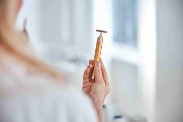 hermosa mujer sosteniendo masajeador en el brazo en el baño - quartz caucasian one person energy fotografías e imágenes de stock