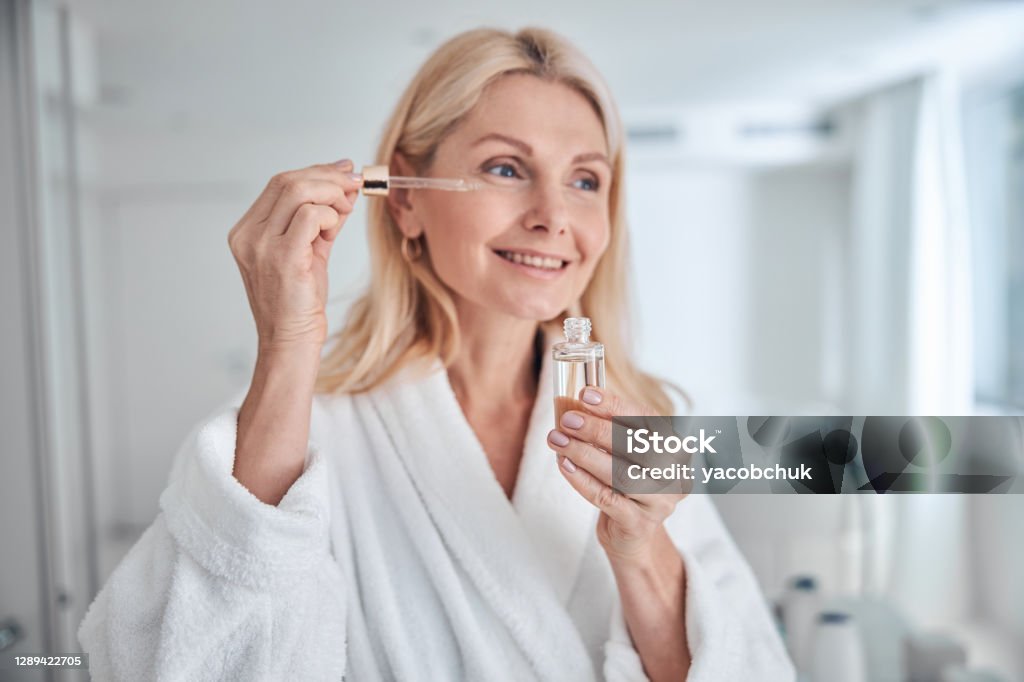 Mujer bastante elegante usando producto cosmético natural para derma hidratado y facial saludable - Foto de stock de Cara humana libre de derechos