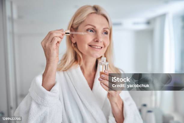 Mujer Bastante Elegante Usando Producto Cosmético Natural Para Derma Hidratado Y Facial Saludable Foto de stock y más banco de imágenes de Cara humana