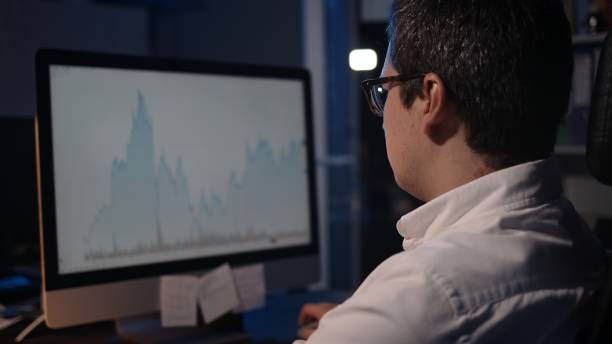 istock Man trader looking at the screen with stock market graphs, home office 1289423876