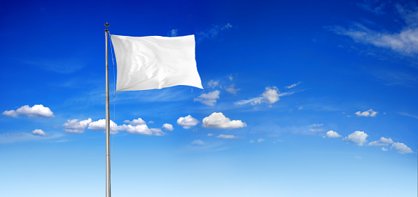 A large American flag blows in the wind against a bright blue sky.