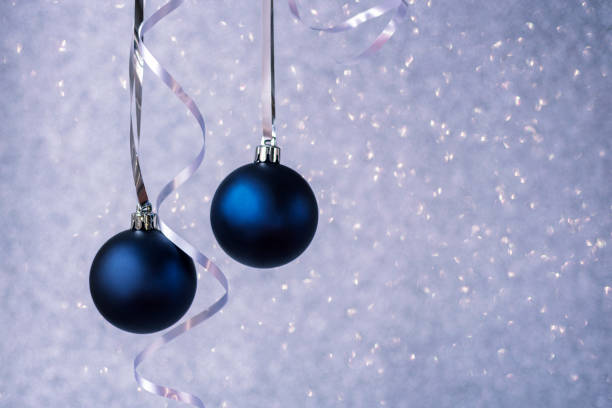 Two blue christmas balls on silver bokeh background. Minimal winter composition. New Year concept, copy space.