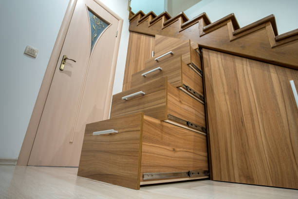 istock Modern architecture interior with luxury hallway with glossy wooden stairs in multi-storey house. Custom built pullout cabinets on glides in slots under stairs. Use of space for storage. 1289426578