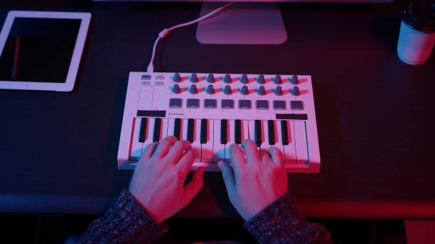 istock Top view of hands using midi keyboard in home studio with neon lights 1289429990