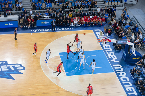 High angle view of basketball player in red jersey throwing a ball to the hoop during the match in court.